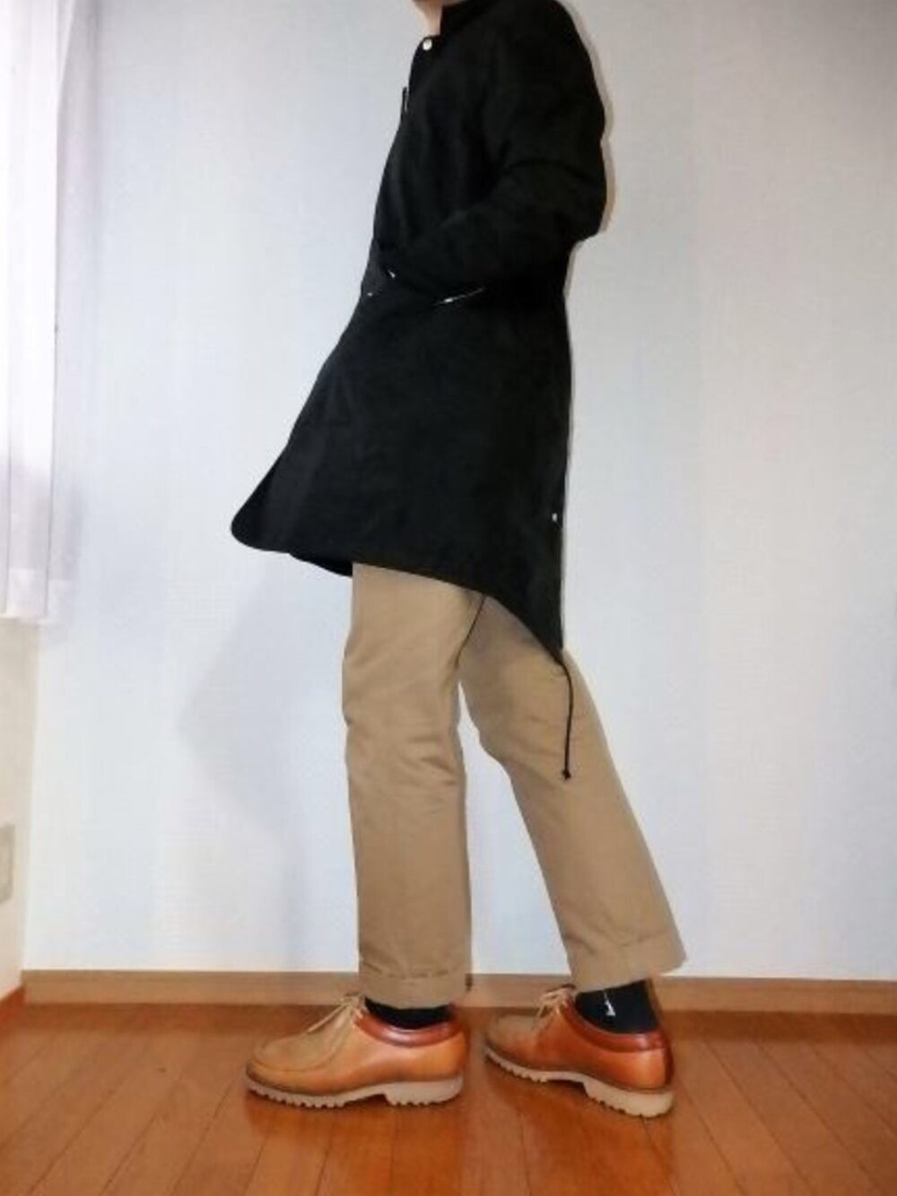 ブラック系のモッズコート、ベージュ系のチノパンツ、ブラウン系のモカシン/デッキシューズを着用したメンズの冬コーディネートの1枚目の写真