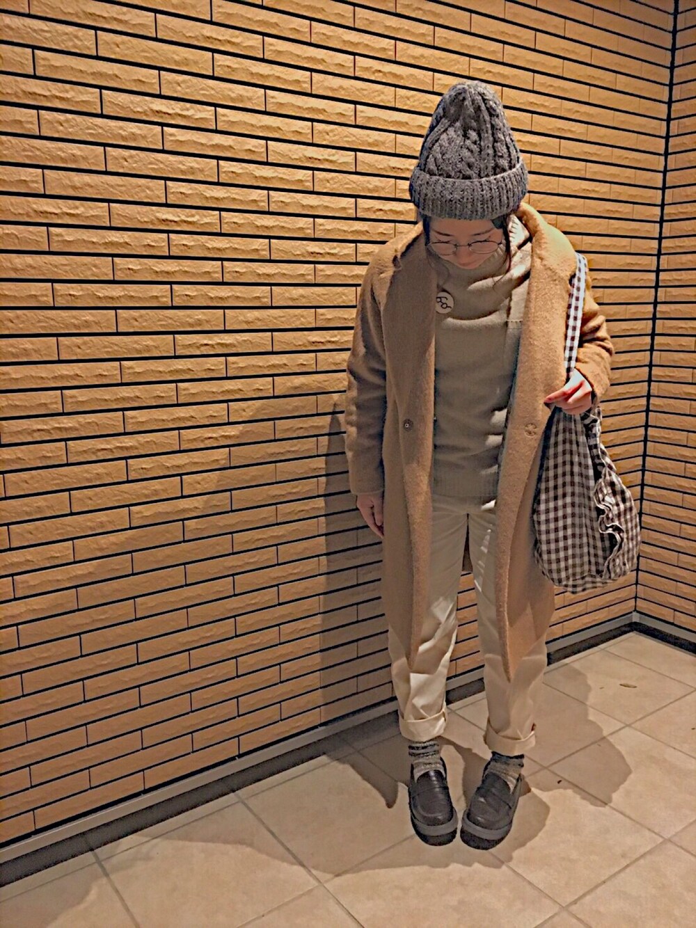 ベージュ系のニット/セーター、ベージュ系のチェスターコート、ホワイト系のチノパンツを着用したレディースの冬コーディネートの1枚目の写真