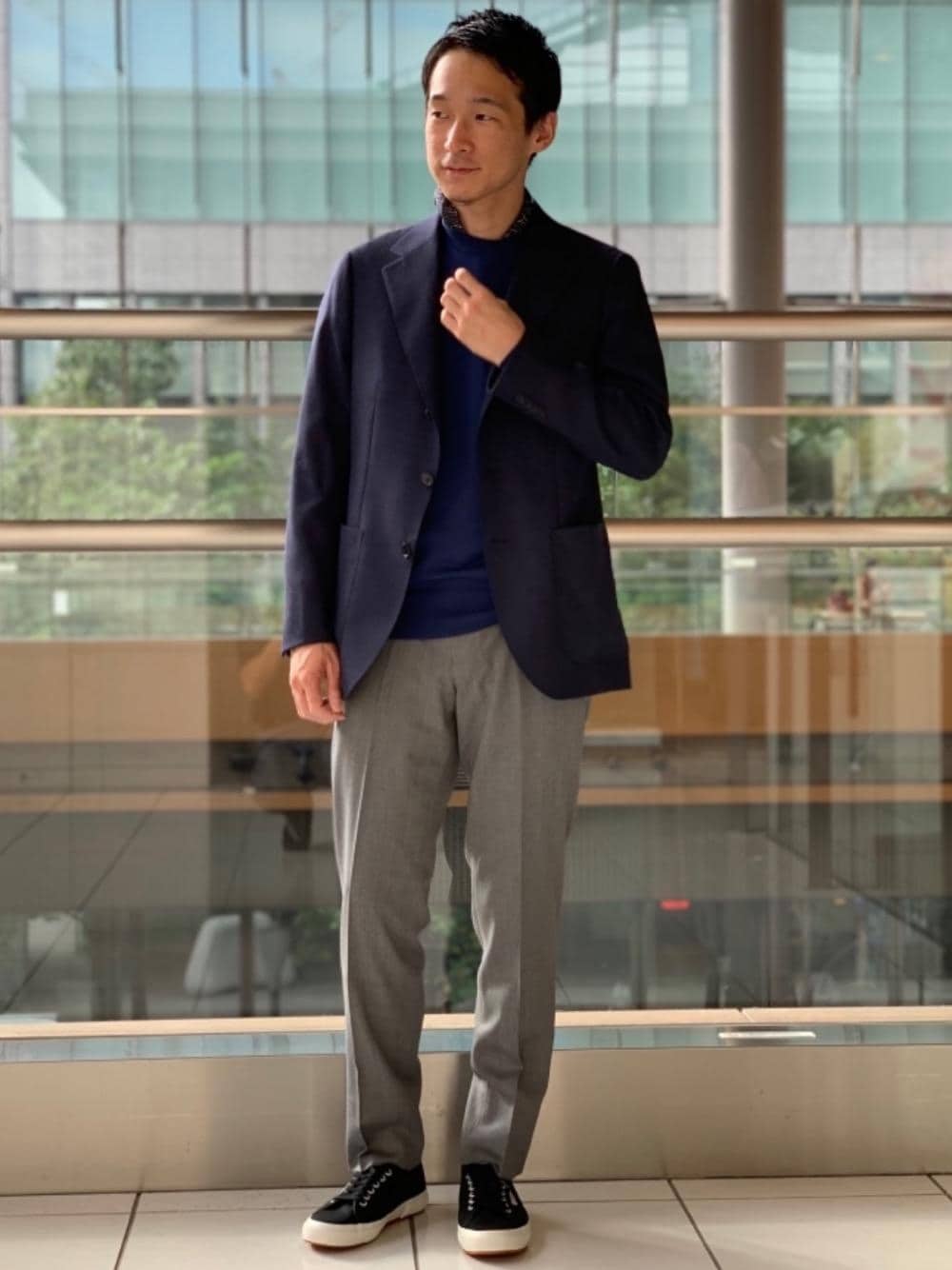 ブラック系のスニーカー、ブルー系のテーラードジャケット、ブルー系のニット/セーターを着用したメンズの秋コーディネートの1枚目の写真