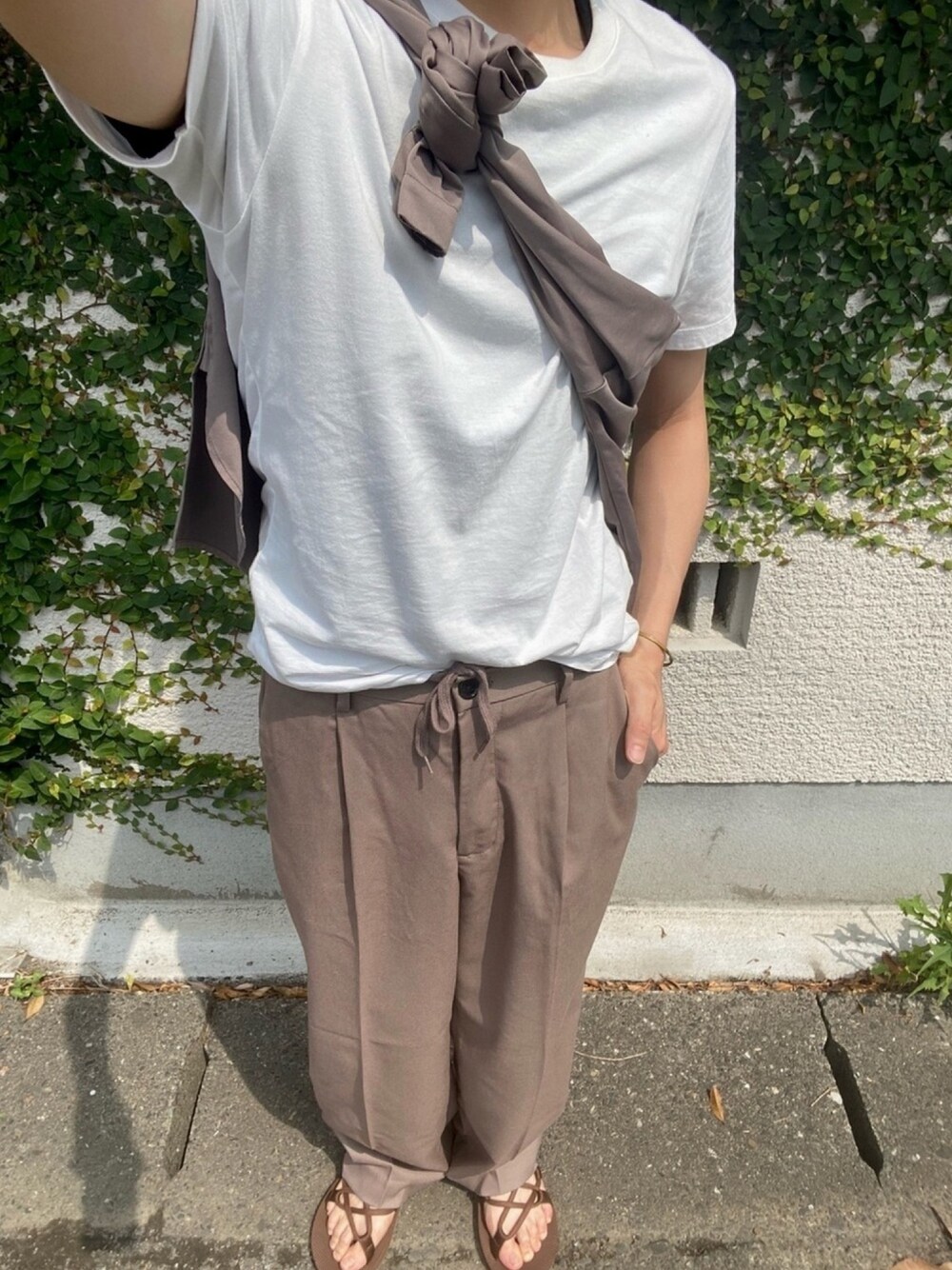 ホワイト系のTシャツ/カットソー、ベージュ系のパンツ、ブラウン系のサンダルを着用したメンズの夏コーディネートの1枚目の写真