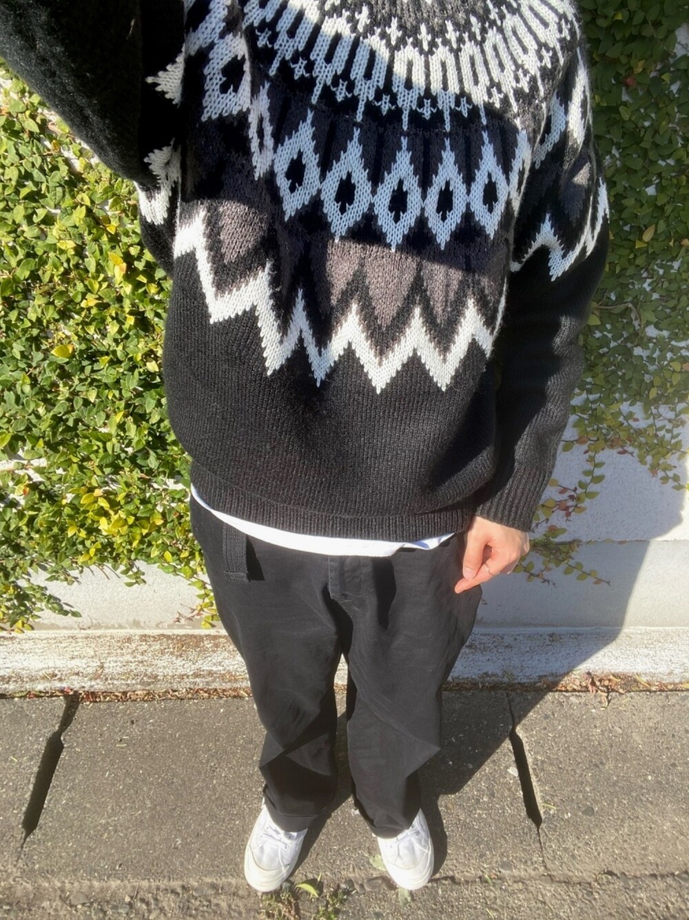 ブラック系のニット/セーター、ホワイト系のTシャツ/カットソー、ブラック系のスラックスを着用したメンズの冬コーディネートの1枚目の写真
