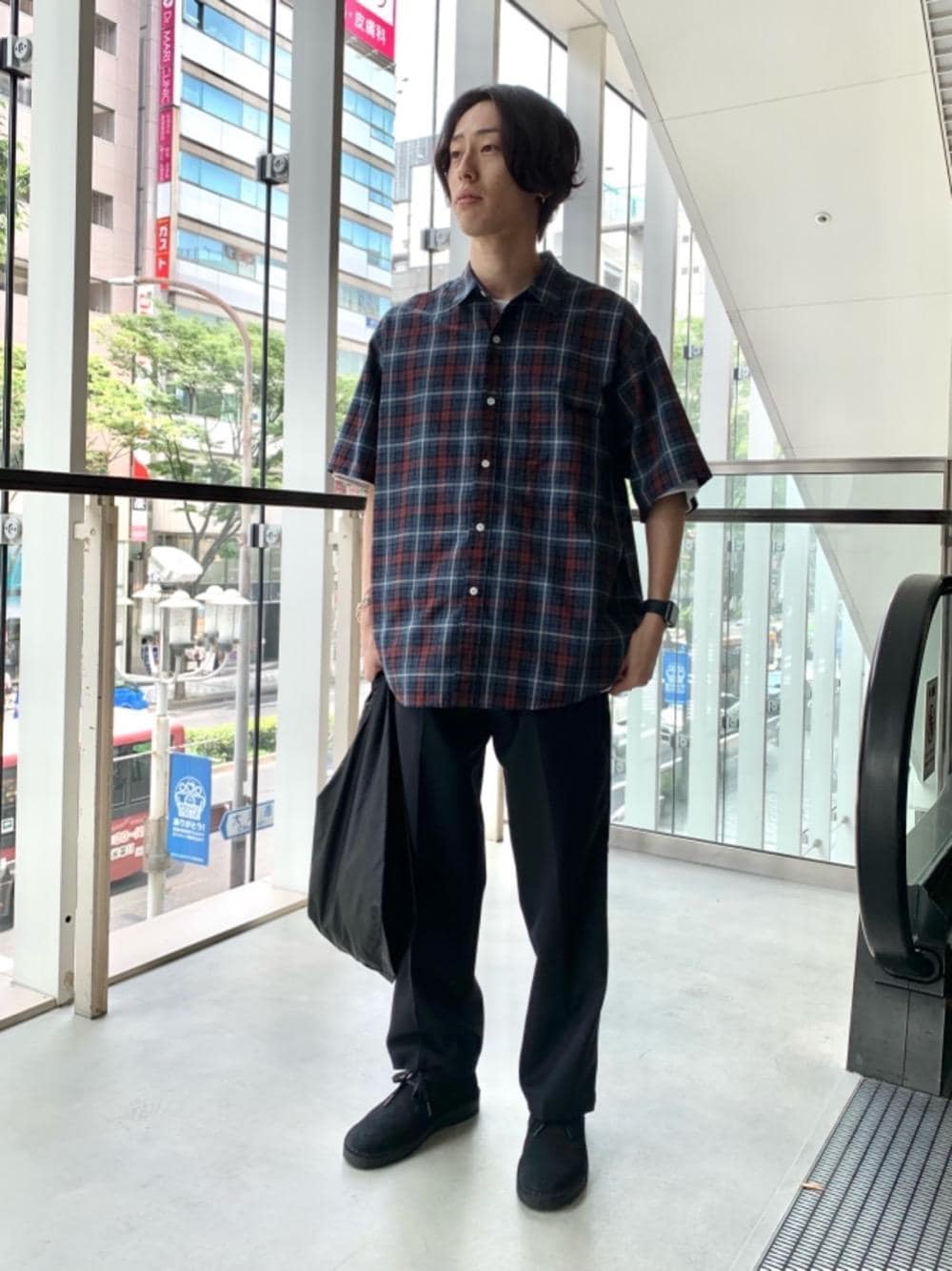 ブラック系のトートバッグ、ブラック系のブーツ、ブルー系のスラックスを着用したメンズの夏コーディネートの1枚目の写真