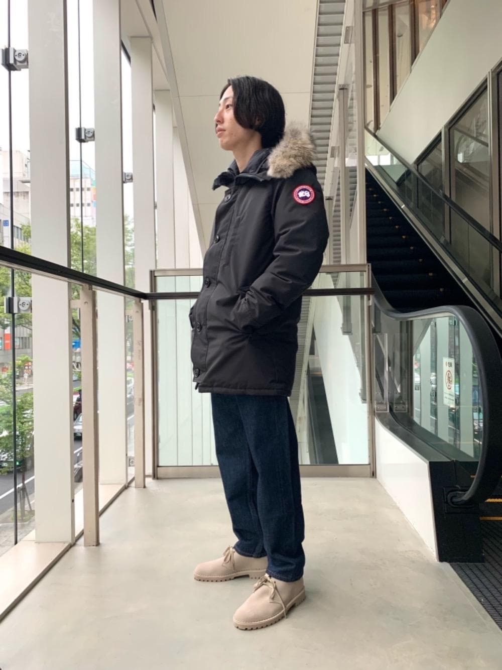 ブルー系のデニムパンツ、ベージュ系のブーツを着用したメンズの秋コーディネートの1枚目の写真