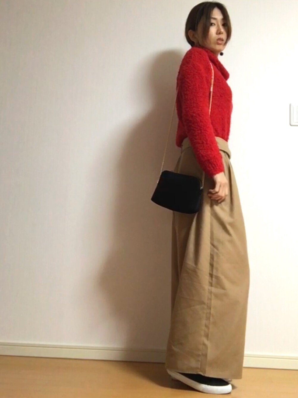 レッド系のニット/セーター、ベージュ系のその他パンツ、ブラック系のスニーカーを着用したレディースの冬コーディネートの1枚目の写真