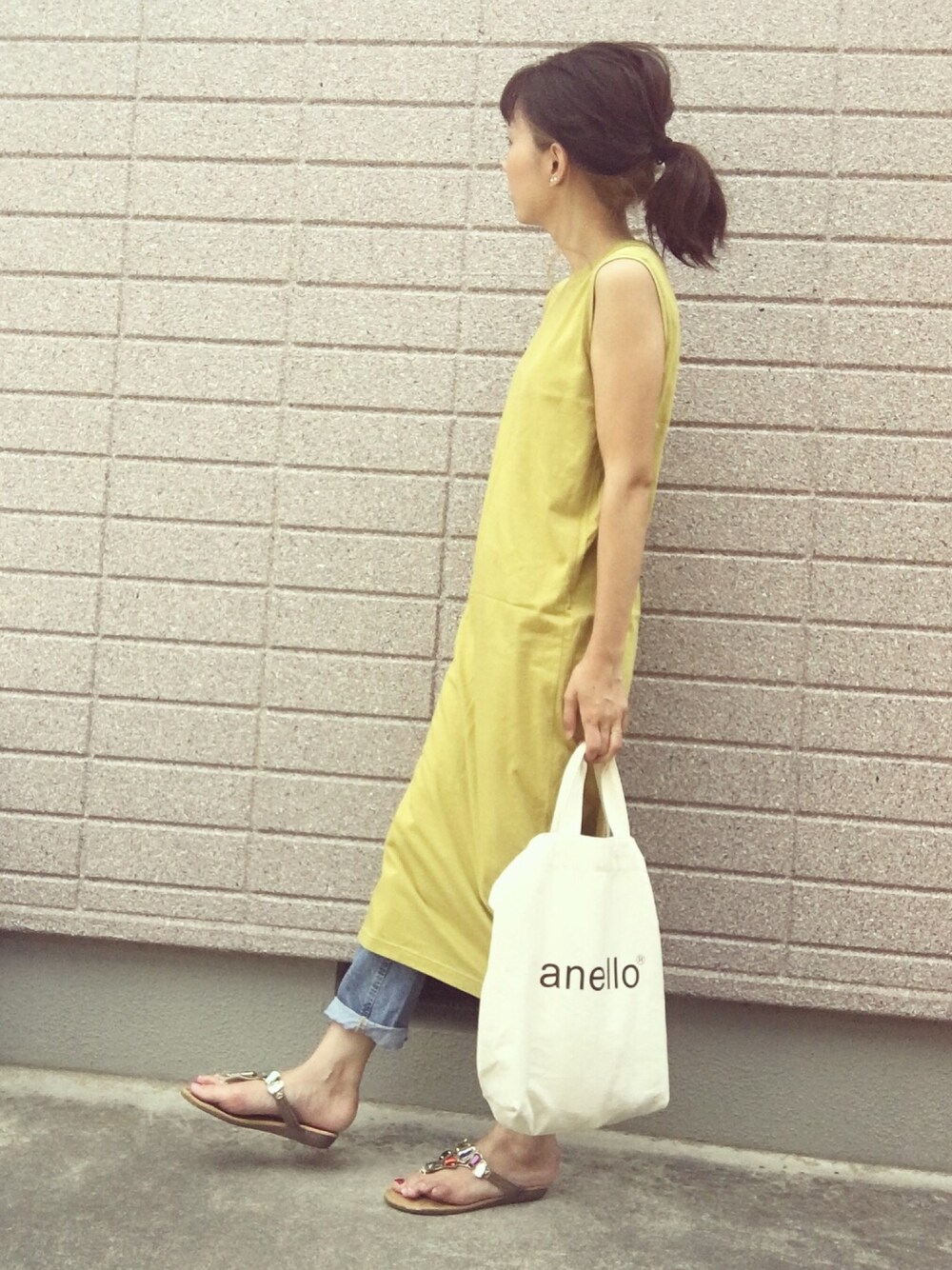 イエロー系のワンピース、ブルー系のデニムパンツ、ホワイト系のトートバッグを着用したレディースの夏コーディネートの1枚目の写真