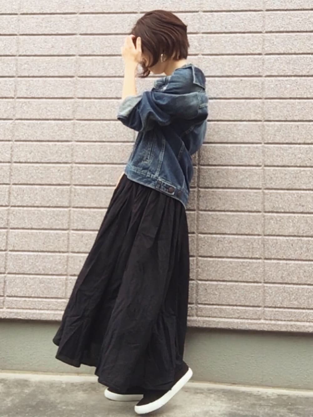ブルー系のデニムジャケット、ブラック系のスカート、ブラック系のスニーカーを着用したレディースの夏コーディネートの1枚目の写真