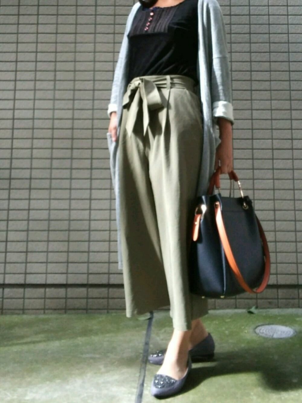 グレー系のパンプス、ブラック系のトートバッグ、グリーン系のその他パンツを着用したレディースの秋コーディネートの1枚目の写真