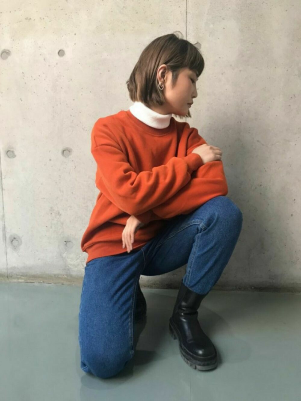 オレンジ系のスウェット、ブルー系のデニムパンツ、その他のトップスを着用したレディースの秋コーディネートの1枚目の写真