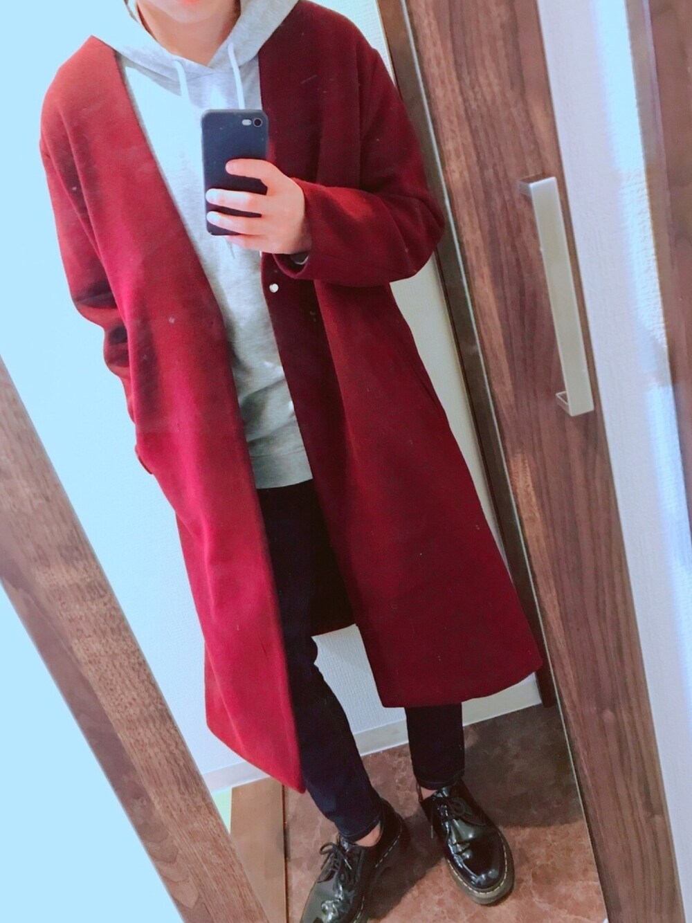 グレー系のパーカー、レッド系のノーカラーコート、ブラック系のデニムパンツを着用したメンズの秋コーディネートの1枚目の写真