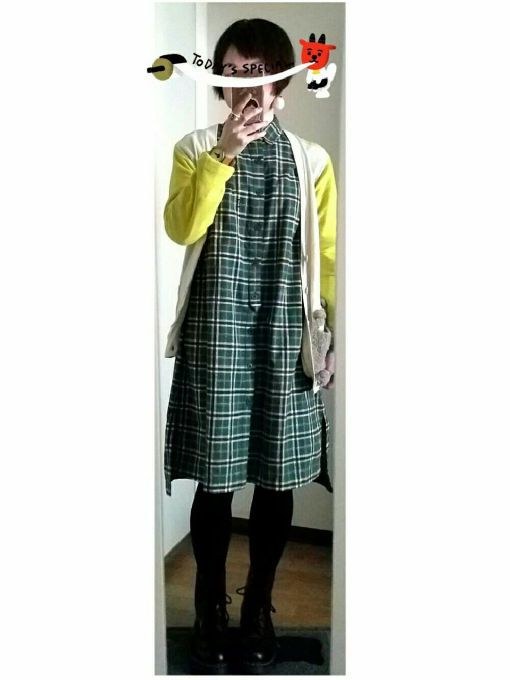 グリーン系のワンピース、ホワイト系のカーディガン/ボレロ、ブラック系のブーツを着用したレディースの冬コーディネートの1枚目の写真