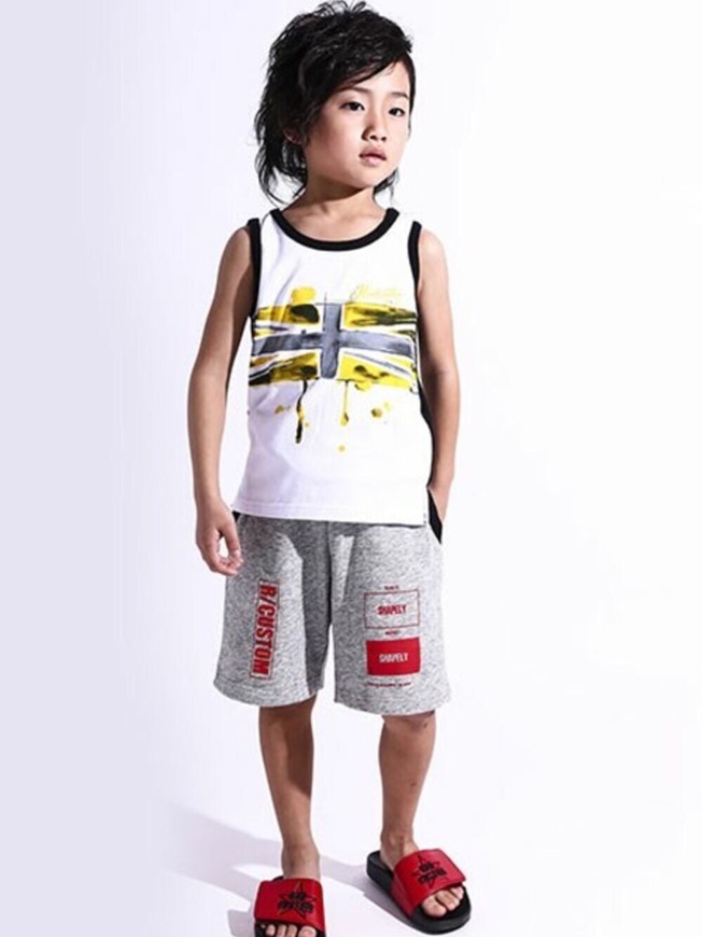 レッド系のタンクトップ、ブラック系のスウェットパンツ、ブラック系のサンダルを着用したキッズの夏コーディネートの1枚目の写真