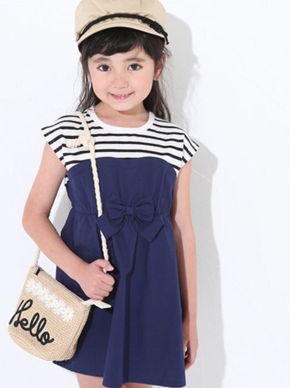 ベージュ系のワンピース、ベージュ系のショルダーバッグ、ブラック系のサンダルを着用したキッズの夏コーディネートの1枚目の写真