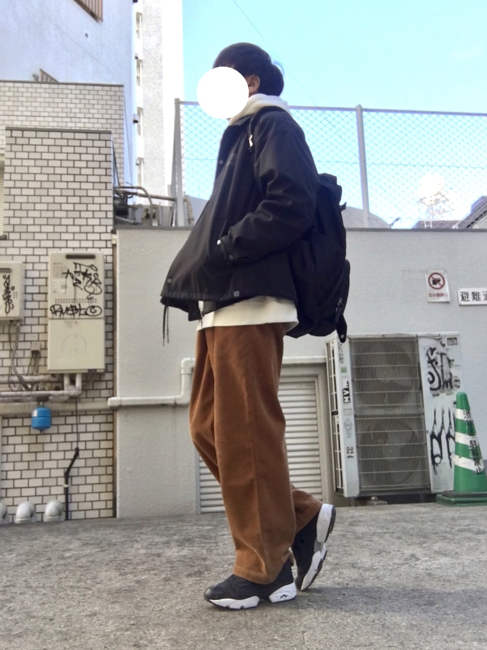 ブラック系のスニーカー、ブラウン系のパンツ、ホワイト系のパーカーを着用したメンズの冬コーディネートの1枚目の写真