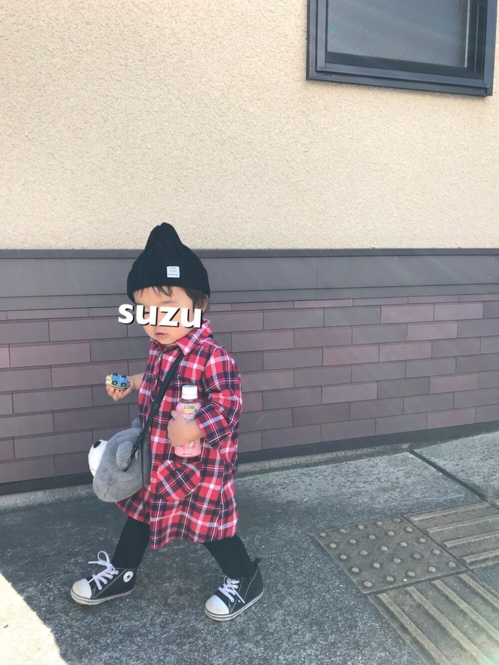 レッド系のシャツワンピース、グレー系のショルダーバッグ、ブラック系のスニーカーを着用したキッズの秋コーディネートの1枚目の写真