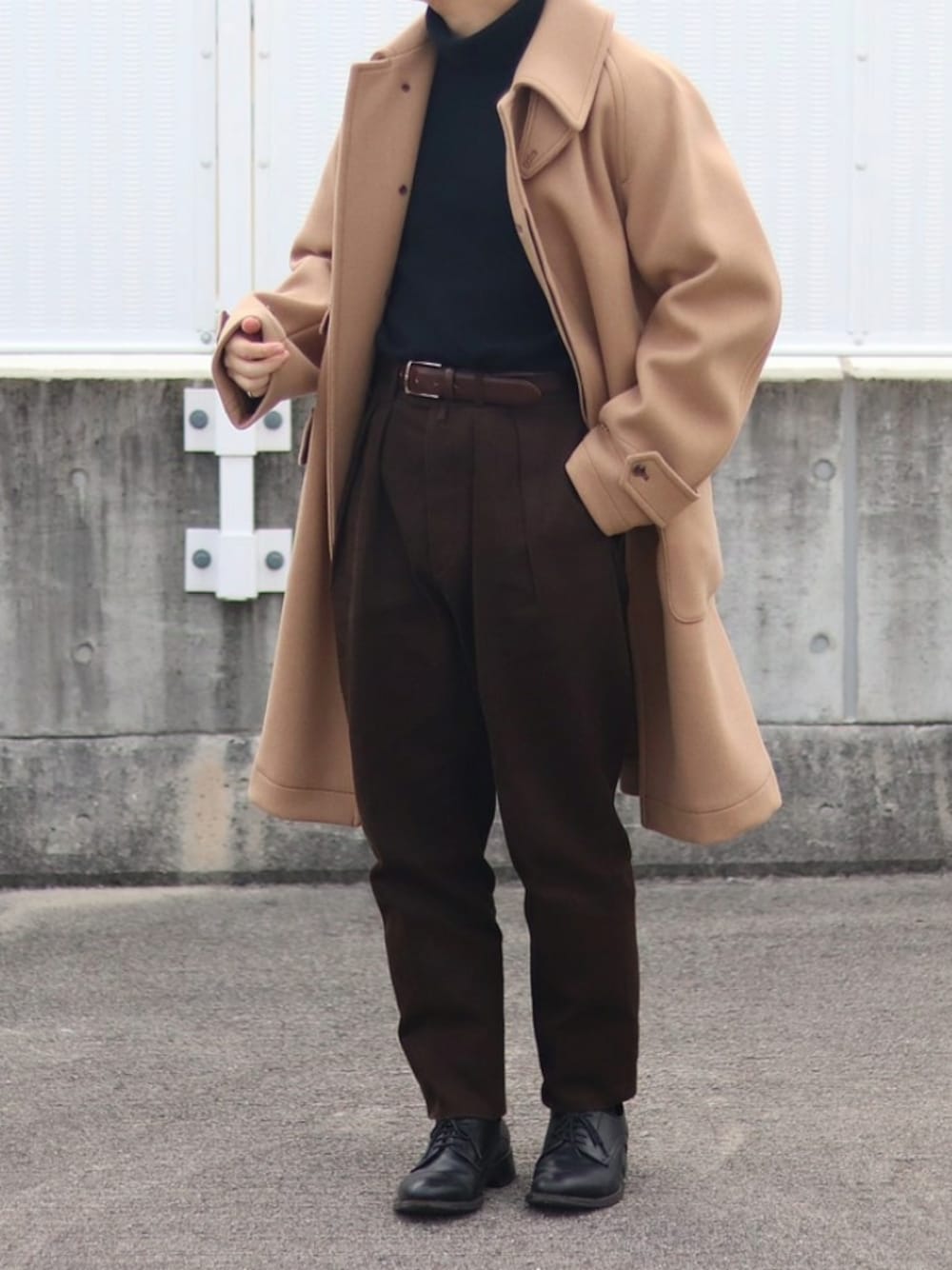 ベージュ系のステンカラーコート、ブラウン系のパンツ、ブラック系のニット/セーターを着用したメンズの冬コーディネートの1枚目の写真