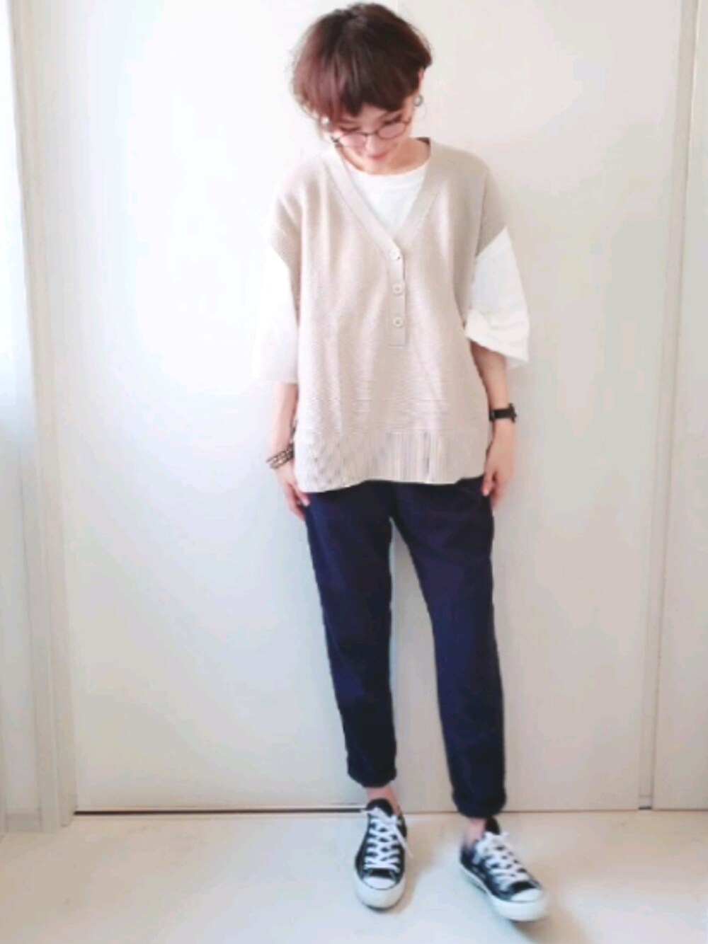 ベージュ系のニット/セーター、ホワイト系のトップス、ブルー系のオールインワン・サロペットを着用したレディースの春コーディネートの1枚目の写真