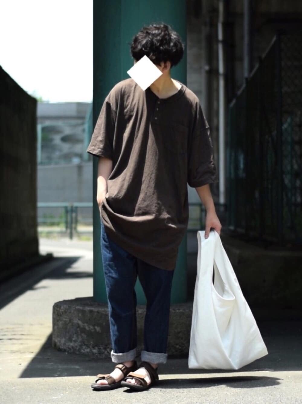 ブラウン系のサンダル、ブルー系のデニムパンツ、ホワイト系のトートバッグを着用したメンズの春コーディネートの1枚目の写真