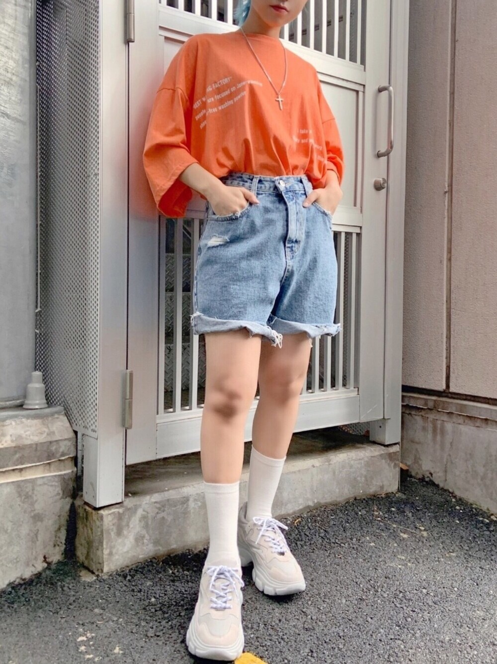 オレンジ系のTシャツ/カットソー、ブルー系のデニムパンツ、グレー系のスニーカーを着用したレディースの夏コーディネートの1枚目の写真