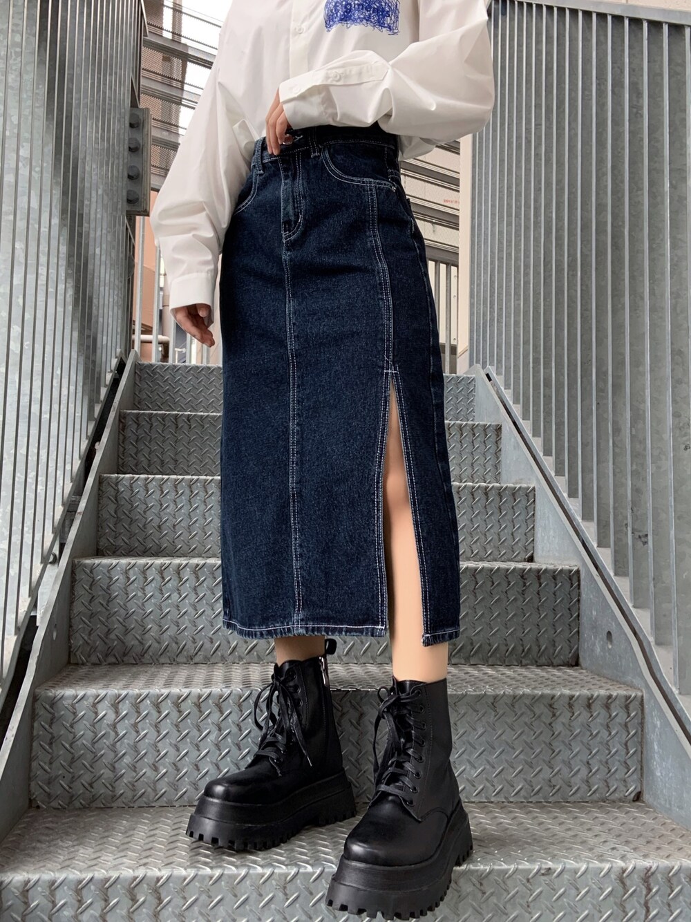 ホワイト系のシャツ/ブラウス、ブルー系のデニムスカート、ブラック系のブーツを着用したレディースの秋コーディネートの1枚目の写真