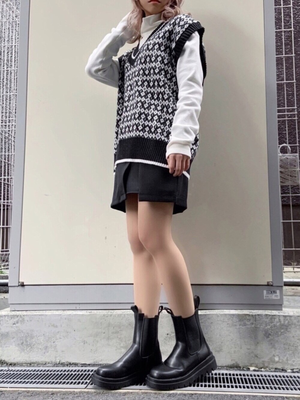 ブラック系のスカート、ブラック系のブーツ、ホワイト系のTシャツ/カットソーを着用したレディースの冬コーディネートの1枚目の写真