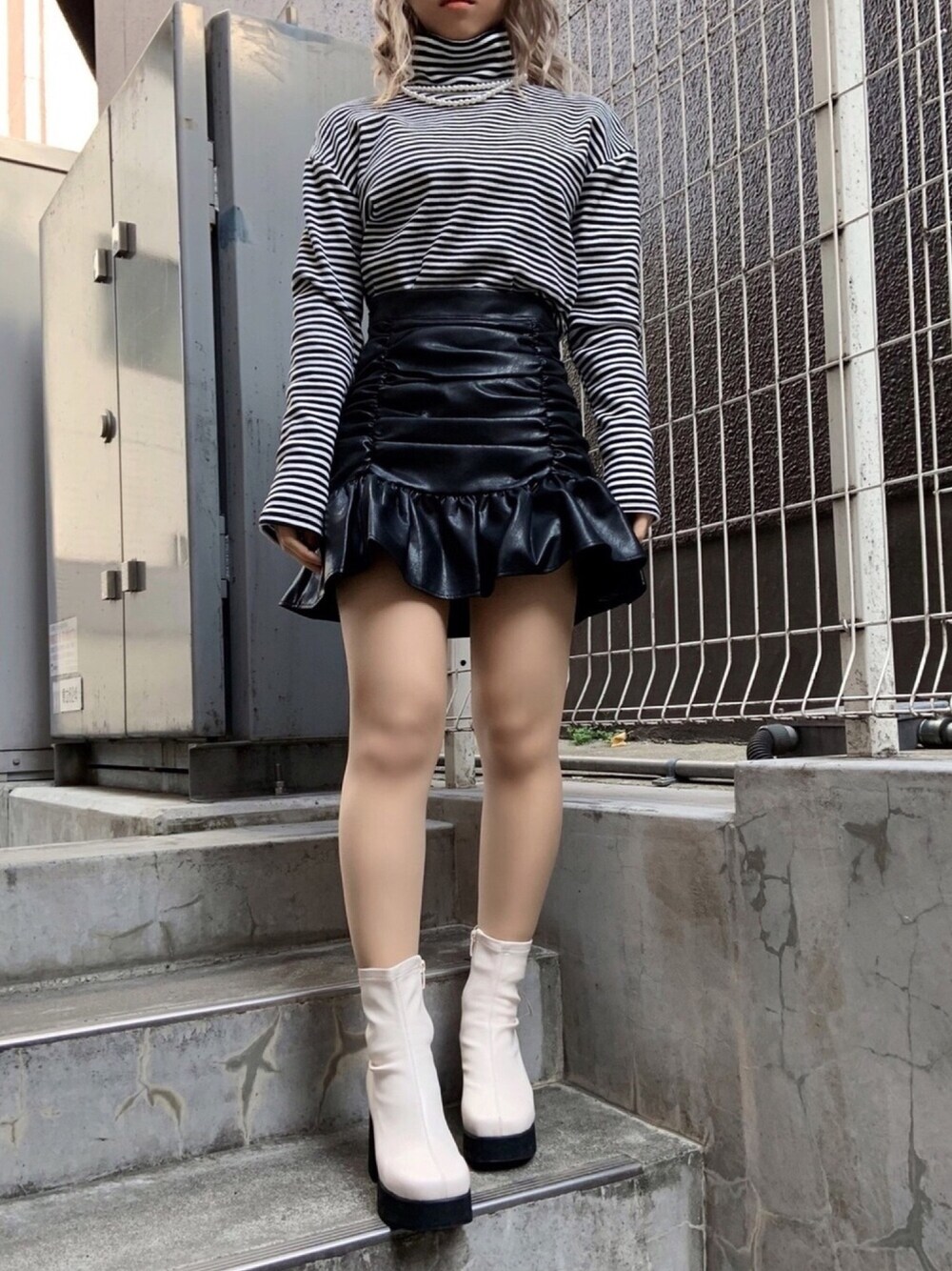 ホワイト系のTシャツ/カットソー、ホワイト系のブーツ、ブラック系のスカートを着用したレディースの冬コーディネートの1枚目の写真