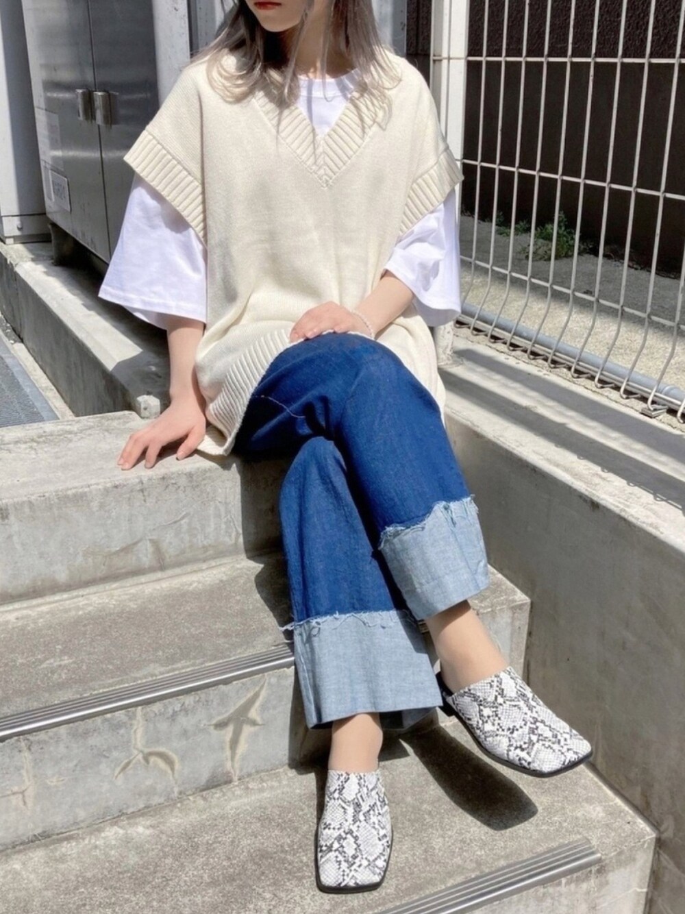 その他のサンダル、ホワイト系のベスト、ブルー系のデニムパンツを着用したレディースの春コーディネートの1枚目の写真