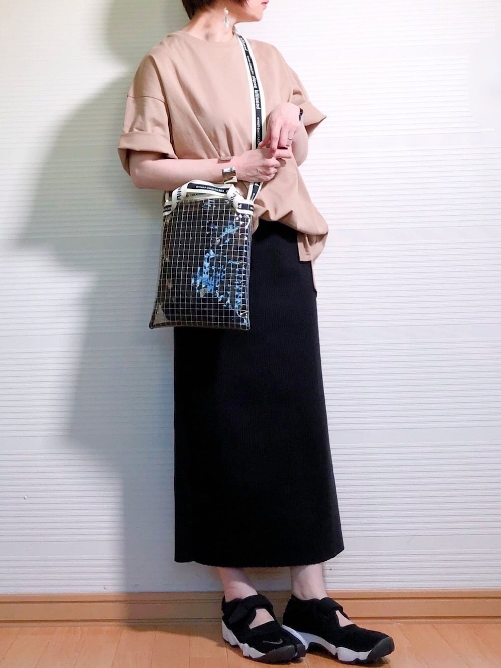 ベージュ系のTシャツ/カットソー、ブラック系のスカート、ブラック系のショルダーバッグを着用したレディースの春コーディネートの1枚目の写真