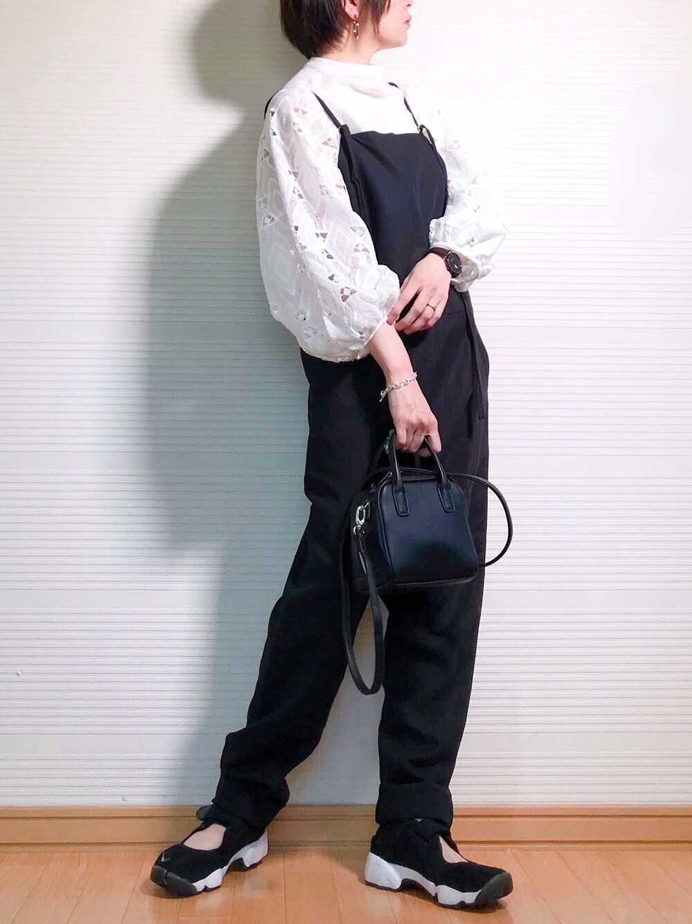 ブラック系のつなぎ/オールインワン、ブラック系のハンドバッグ、ブラック系のスニーカーを着用したレディースの春コーディネートの1枚目の写真