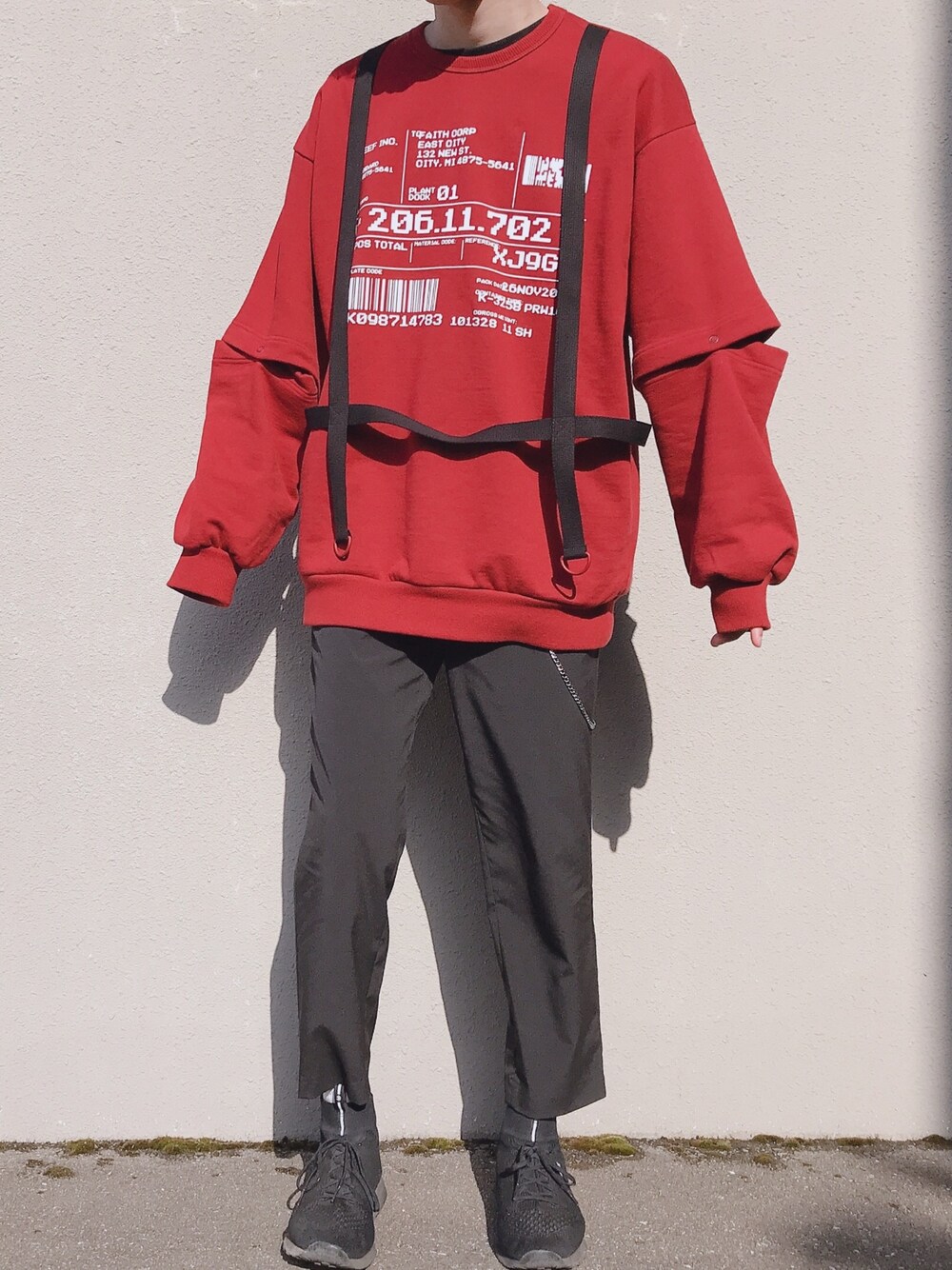 レッド系のスウェット、ブラック系のパンツ、ブラック系のスニーカーを着用したメンズの春コーディネートの1枚目の写真