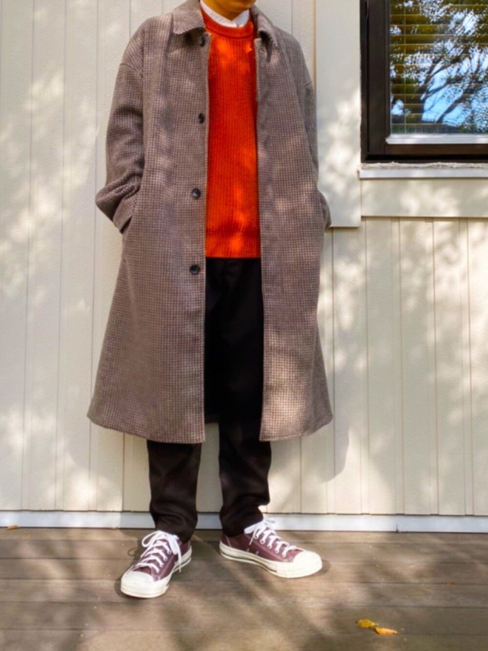 ブラウン系のスラックス、グレー系のスニーカー、オレンジ系のニット/セーターを着用したメンズの冬コーディネートの1枚目の写真