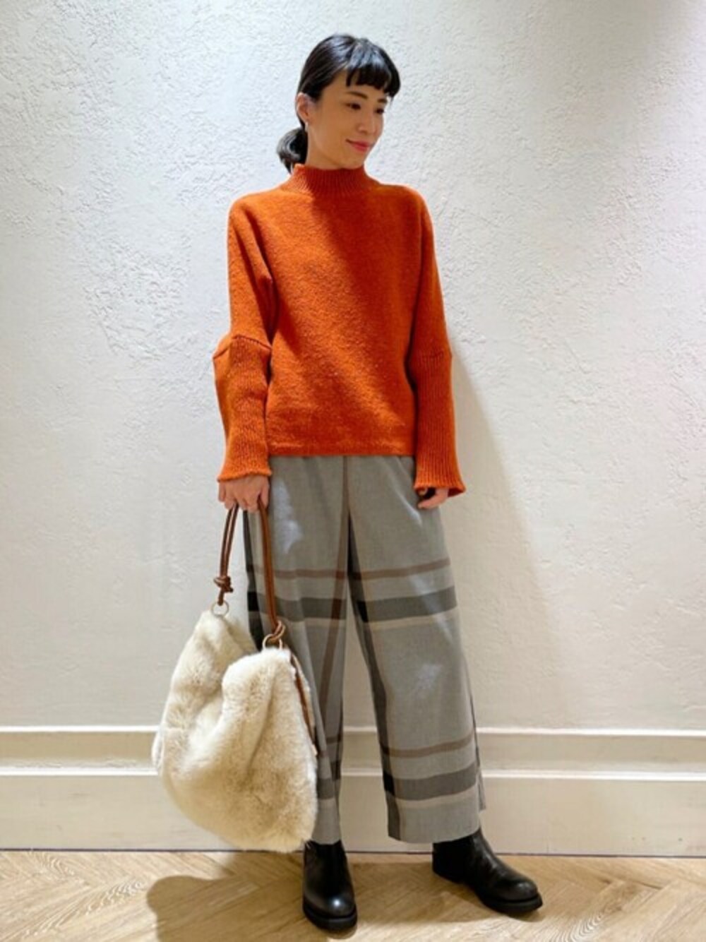 オレンジ系のニット/セーター、グレー系のその他パンツ、ブラック系のその他シューズを着用したレディースの秋コーディネートの1枚目の写真