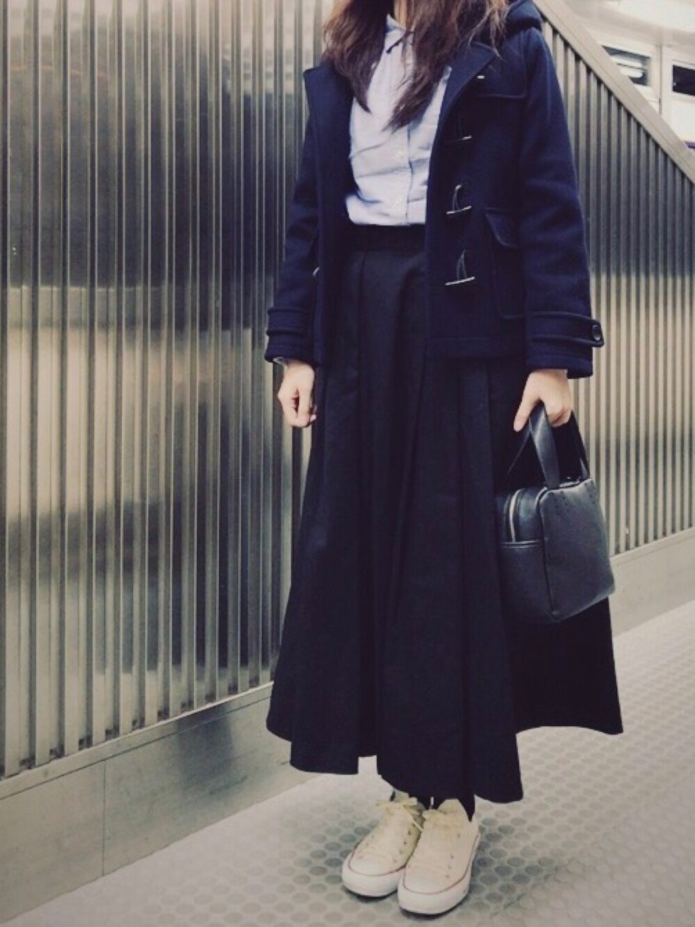 ブルー系のダッフルコート、グリーン系のスカート、ブラック系のハンドバッグを着用したレディースの春コーディネートの1枚目の写真