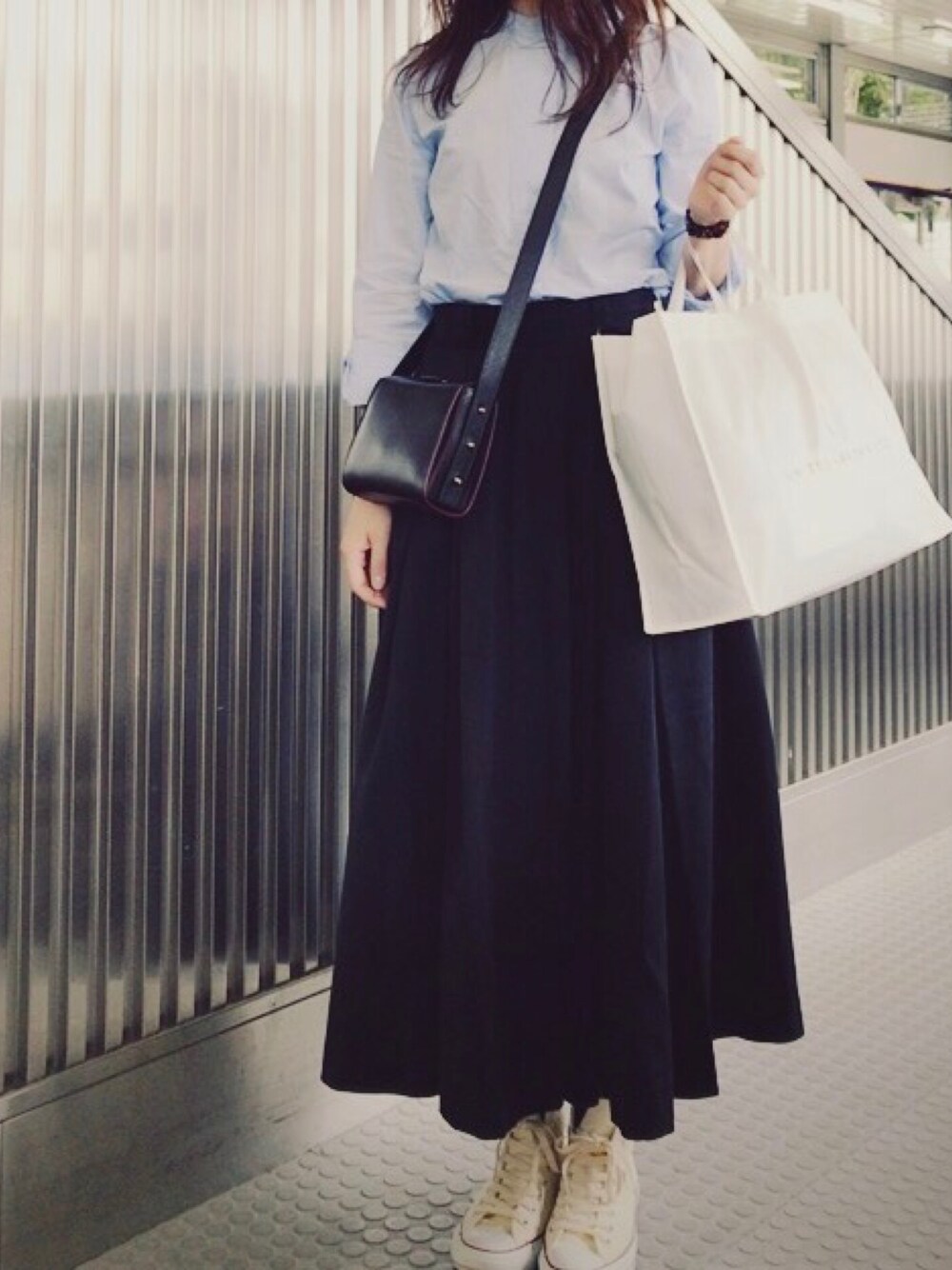 グリーン系のスカート、ゴールド系のショルダーバッグ、ホワイト系のスニーカーを着用したレディースの春コーディネートの1枚目の写真