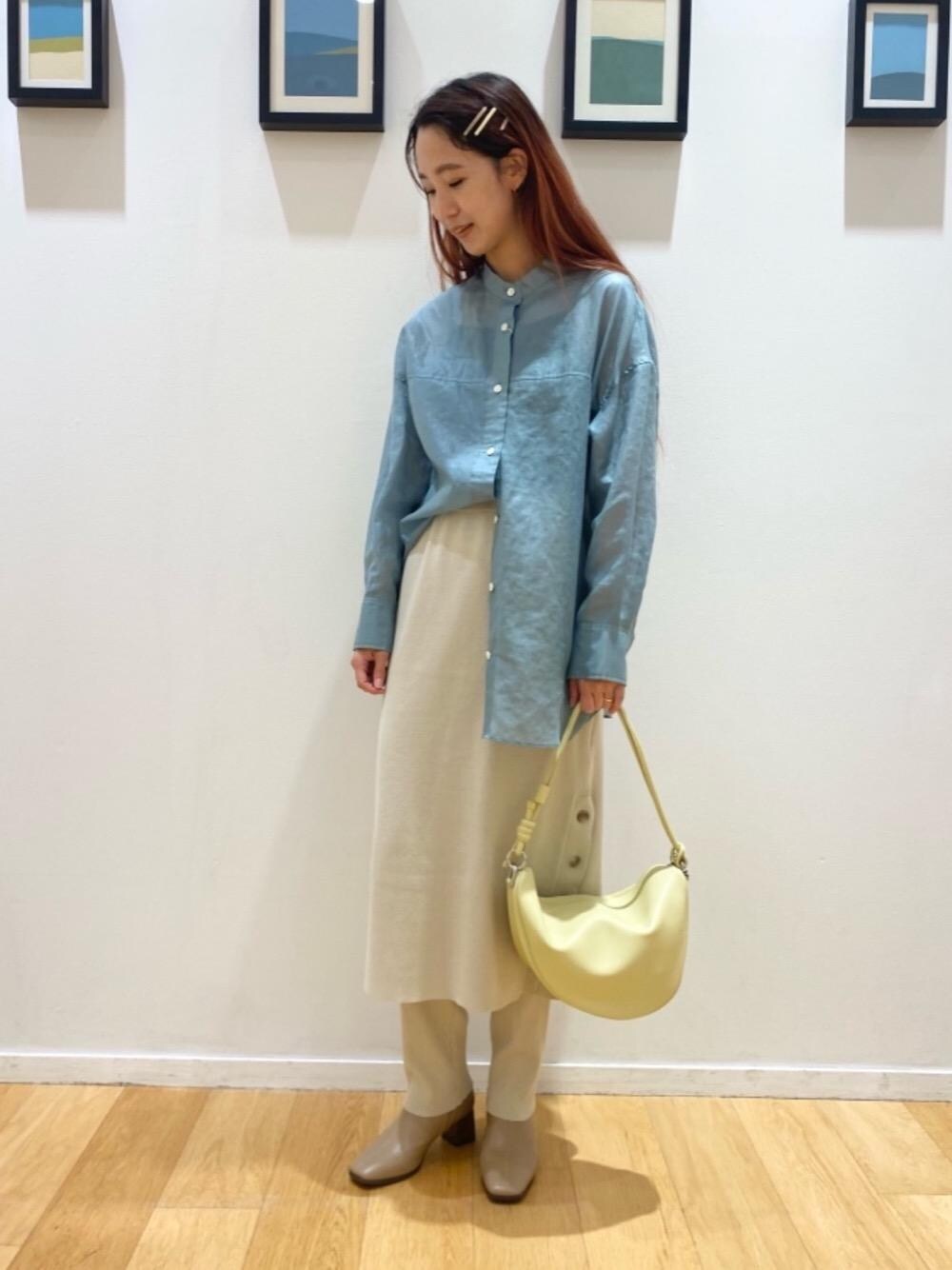 イエロー系のショルダーバッグ、ブラウン系のブーツ、ベージュ系のスカートを着用したレディースの夏コーディネートの1枚目の写真