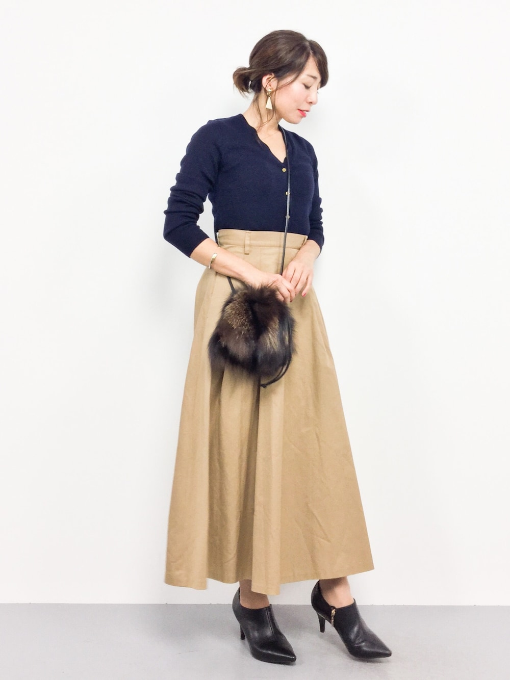 ブラウン系のショルダーバッグ、ベージュ系のスカート、ブルー系のカーディガン/ボレロを着用したレディースの秋コーディネートの1枚目の写真