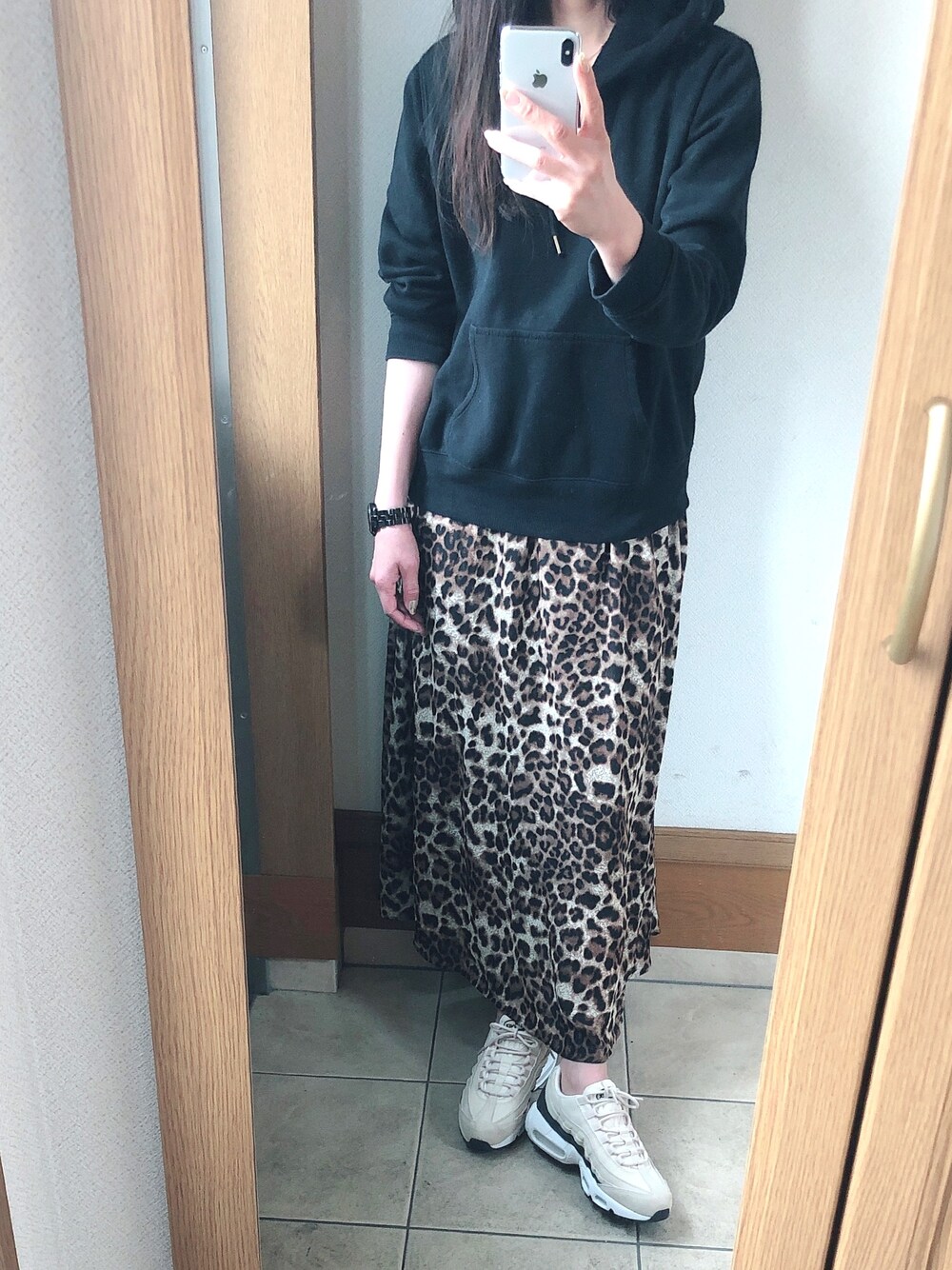 ブラック系のパーカー、ベージュ系のスニーカー、ブラウン系のスカートを着用したレディースの春コーディネートの1枚目の写真