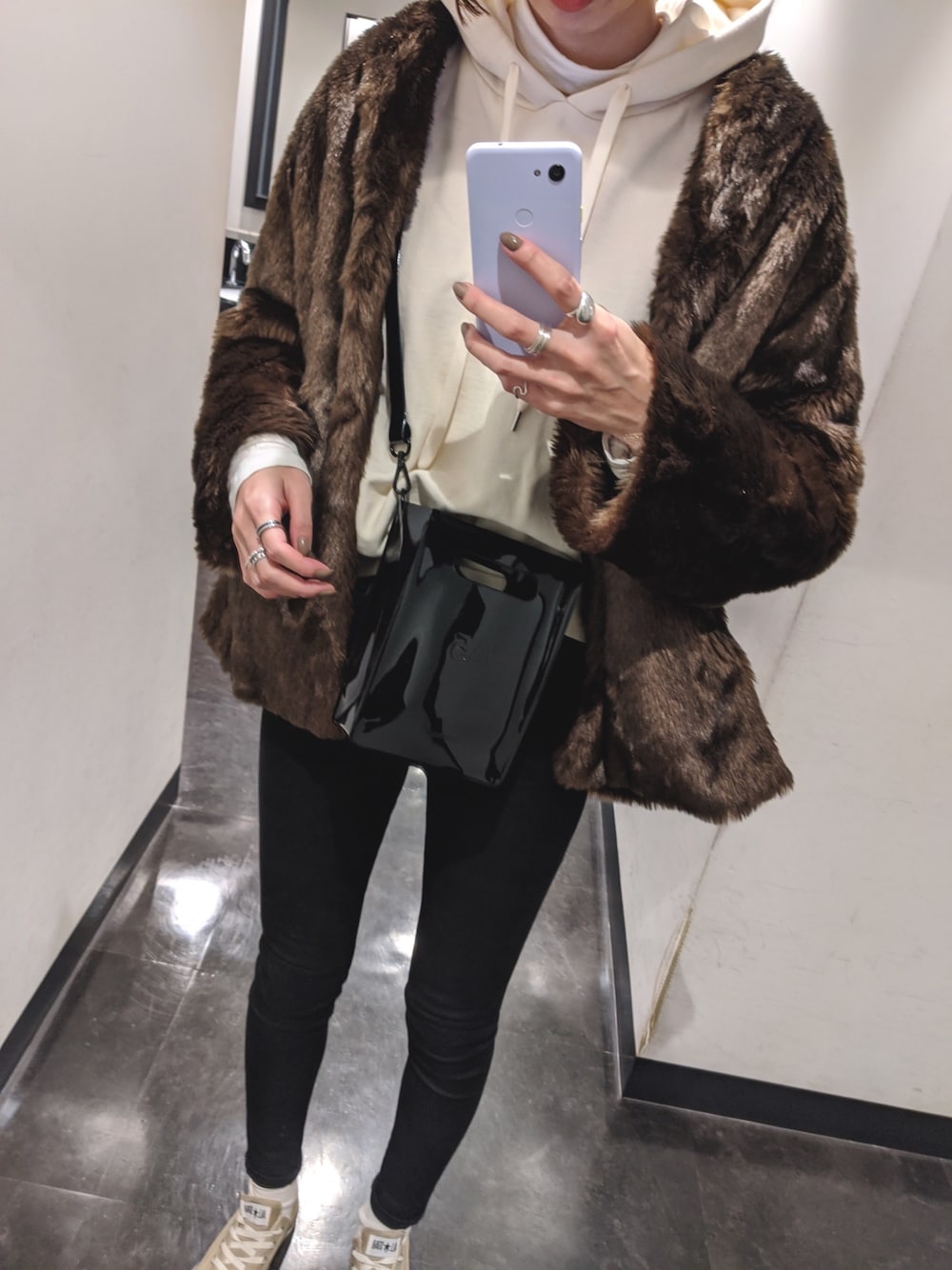 ブラック系のショルダーバッグ、ホワイト系のパーカー、ベージュ系のスニーカーを着用したレディースの秋コーディネートの1枚目の写真