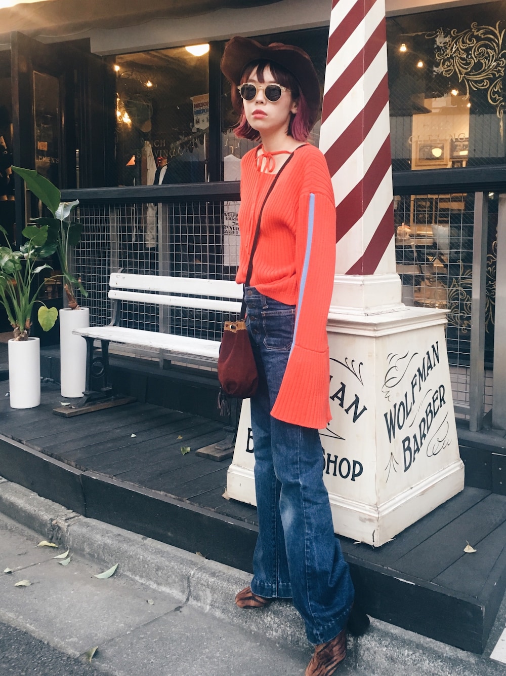 オレンジ系のニット/セーター、ブラウン系のブーツ、ベージュ系のサングラスを着用したレディースの秋コーディネートの1枚目の写真