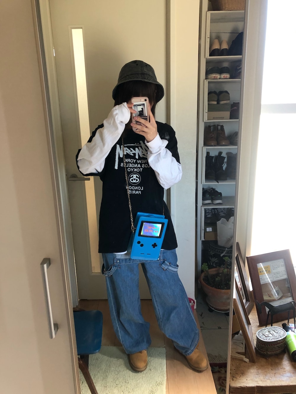 ブラック系のTシャツ/カットソー、ブルー系のサロペット/オーバーオール、ベージュ系のブーツを着用したレディースの春コーディネートの1枚目の写真