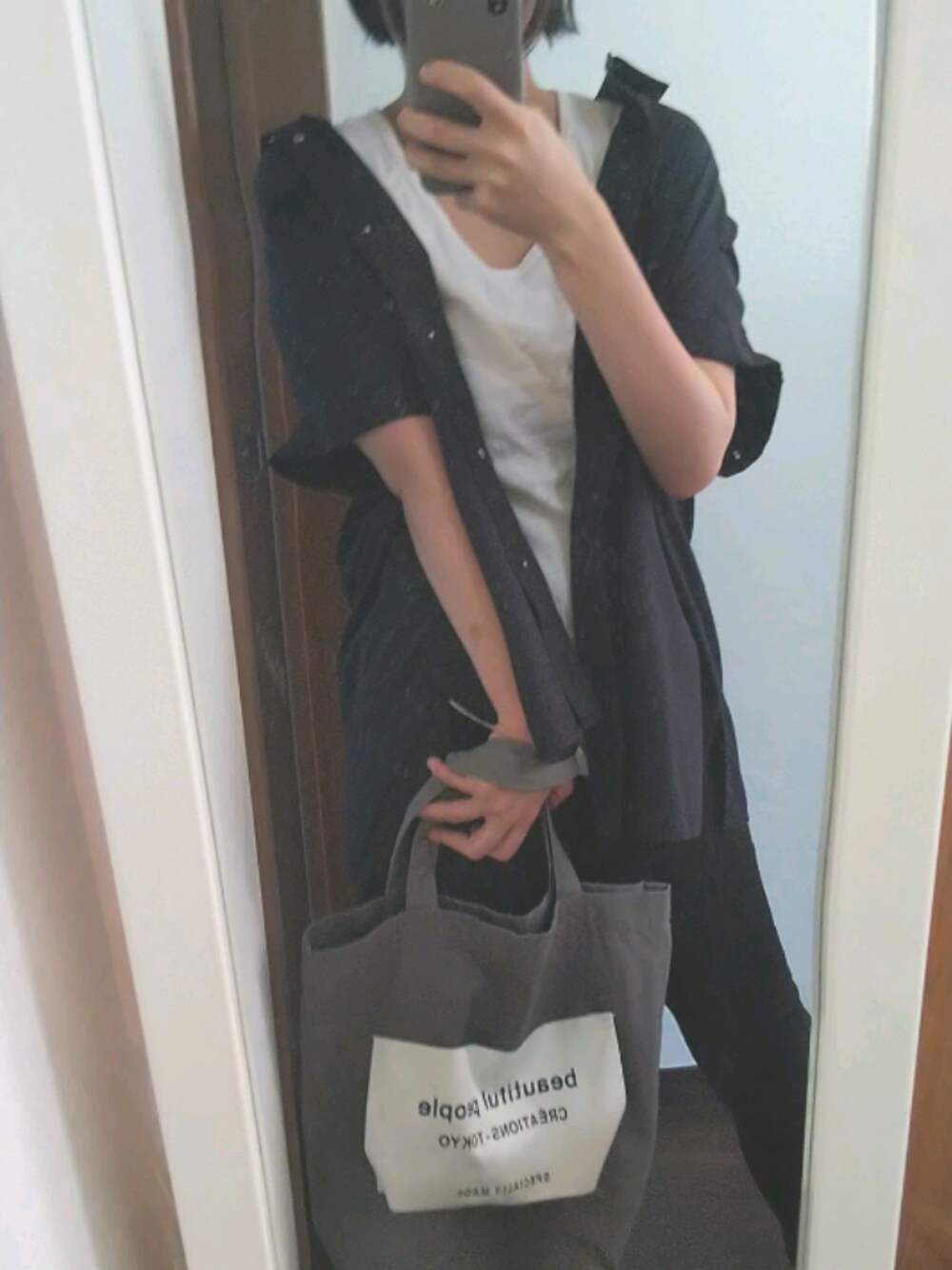 ブラック系のデニムパンツ、ホワイト系のタンクトップを着用したレディースの夏コーディネートの1枚目の写真