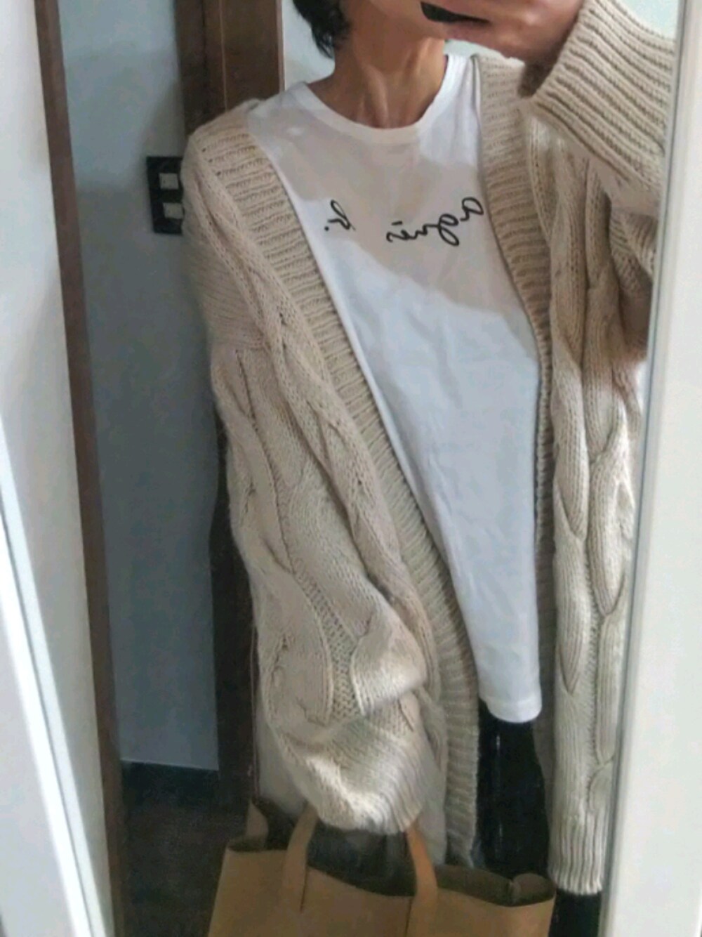 ホワイト系のTシャツ/カットソー、ベージュ系のニット/セーター、ブラック系のデニムパンツを着用したレディースの秋コーディネートの1枚目の写真