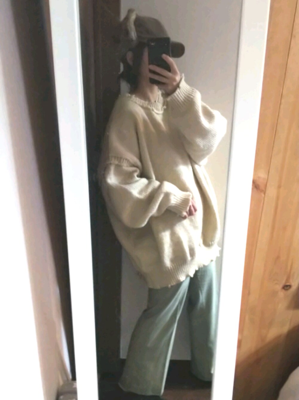 グリーン系のその他パンツ、ホワイト系のニット/セーター、ブラウン系のキャップを着用したレディースの冬コーディネートの1枚目の写真