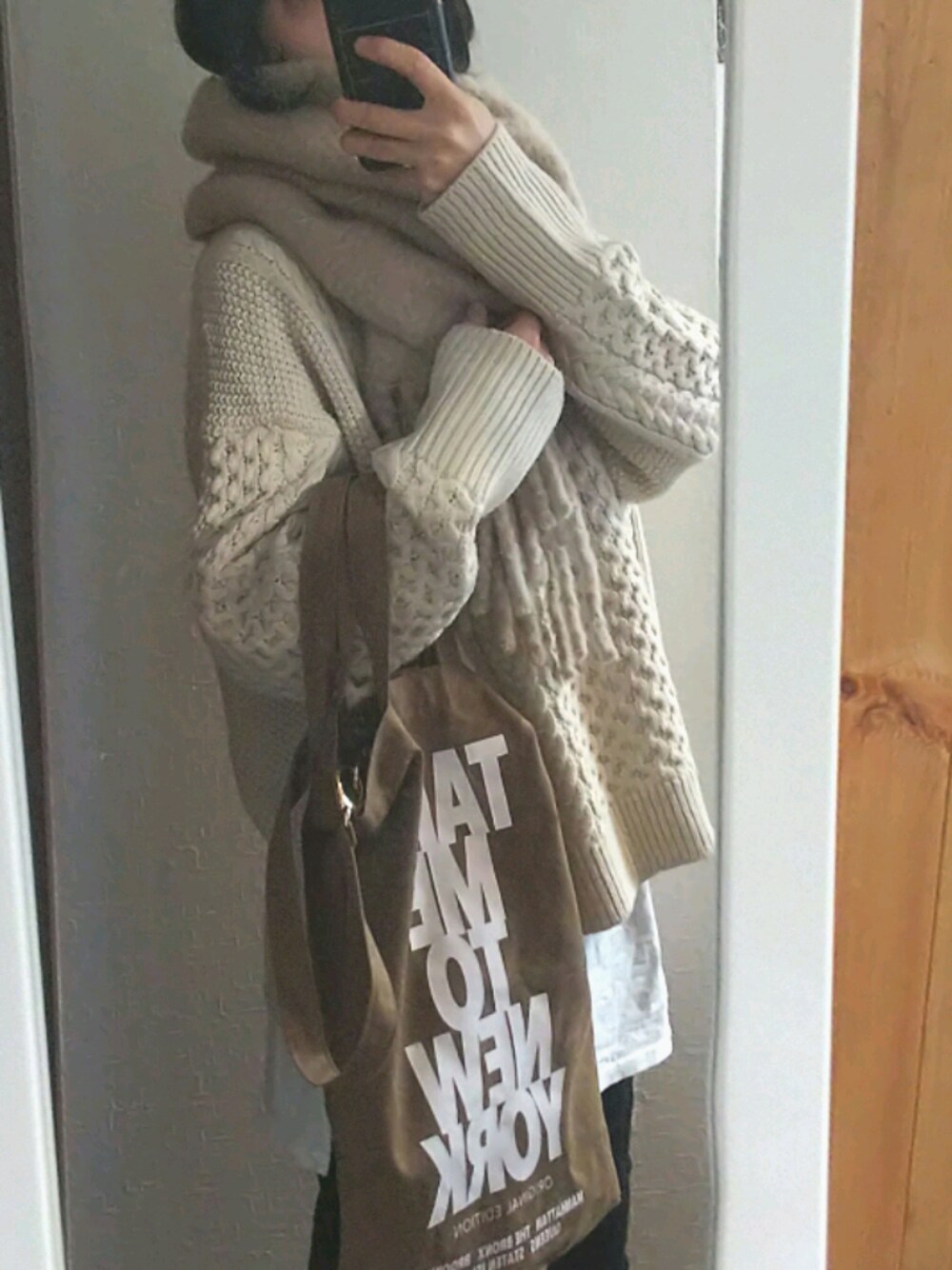 ベージュ系のニット/セーター、ブラック系のデニムパンツ、ベージュ系のマフラーを着用したレディースの冬コーディネートの1枚目の写真