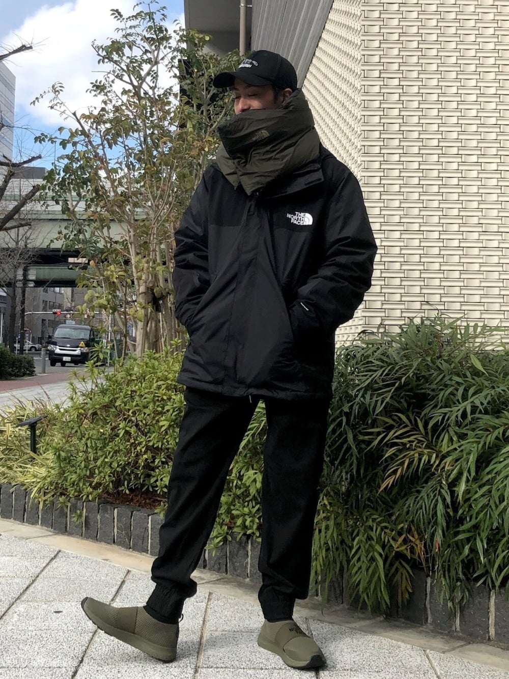 ブラック系のマウンテンパーカー、ブラック系のスウェットパンツ、グリーン系のスニーカーを着用したメンズの冬コーディネートの1枚目の写真