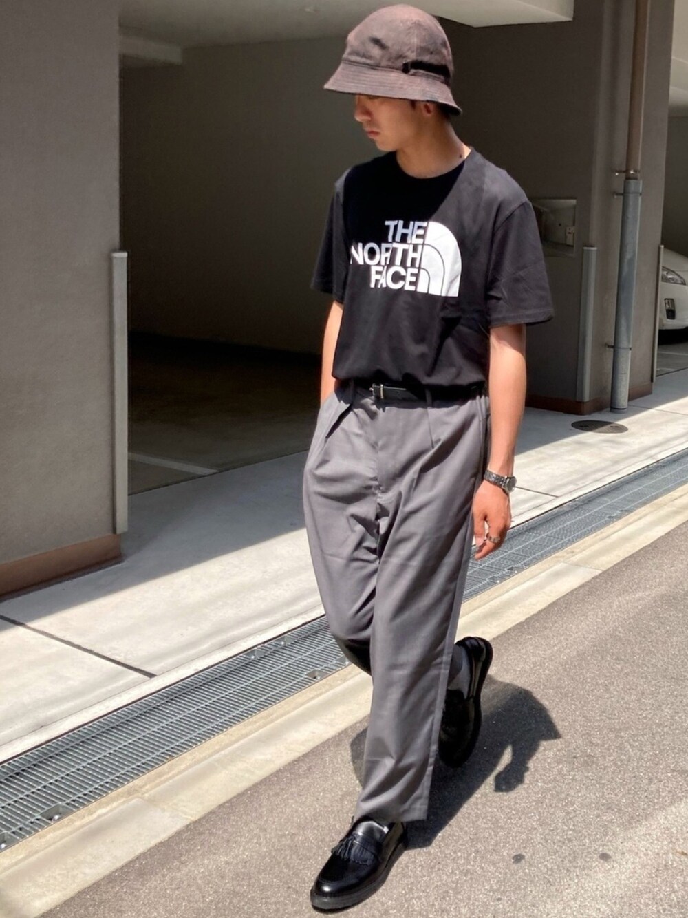 ブラック系のTシャツ/カットソー、ブラック系のスラックス、ブラック系のローファーを着用したメンズの春コーディネートの1枚目の写真