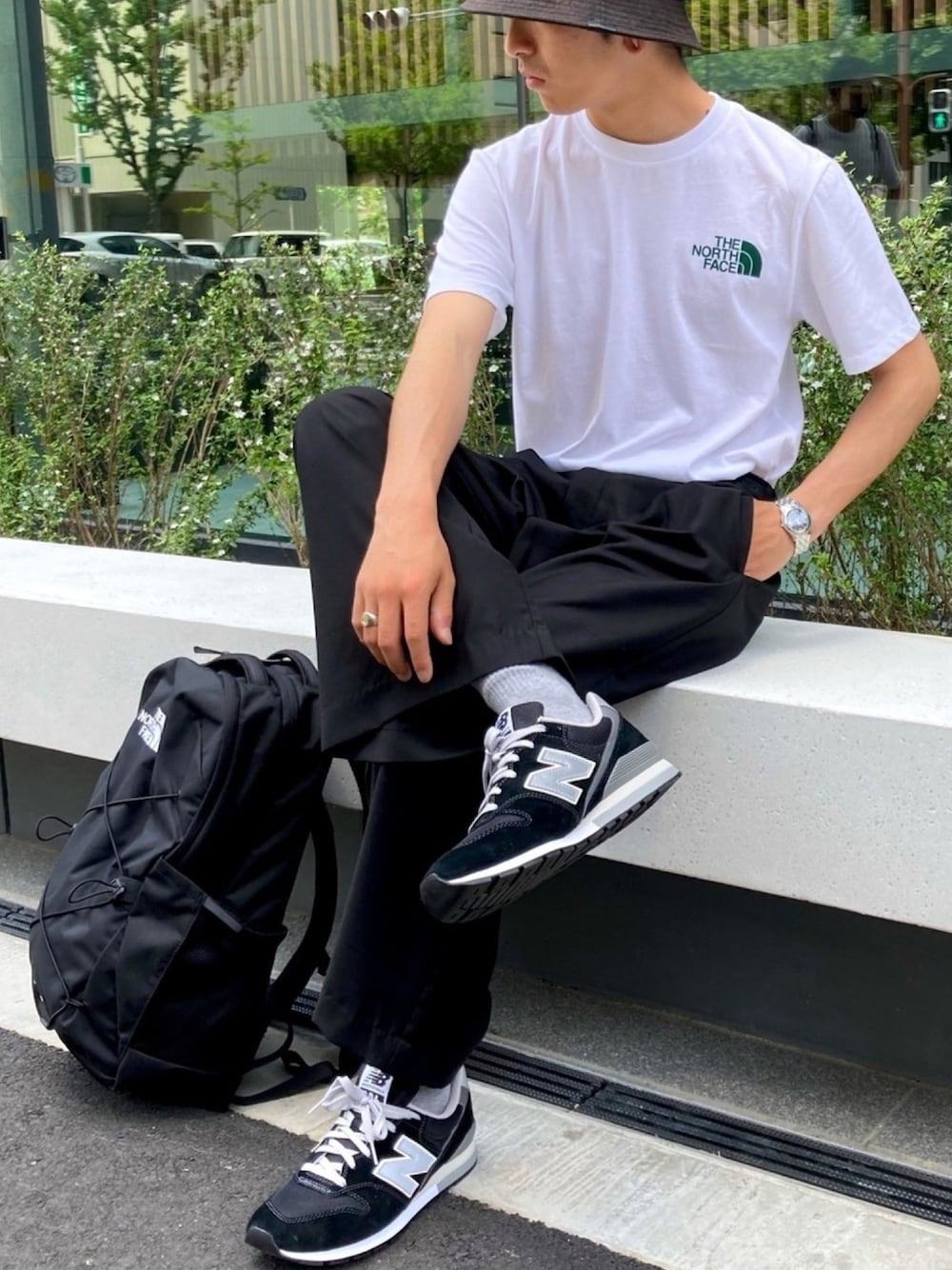 ホワイト系のTシャツ/カットソー、ブラック系のスラックス、ブラック系のスニーカーを着用したメンズの春コーディネートの1枚目の写真
