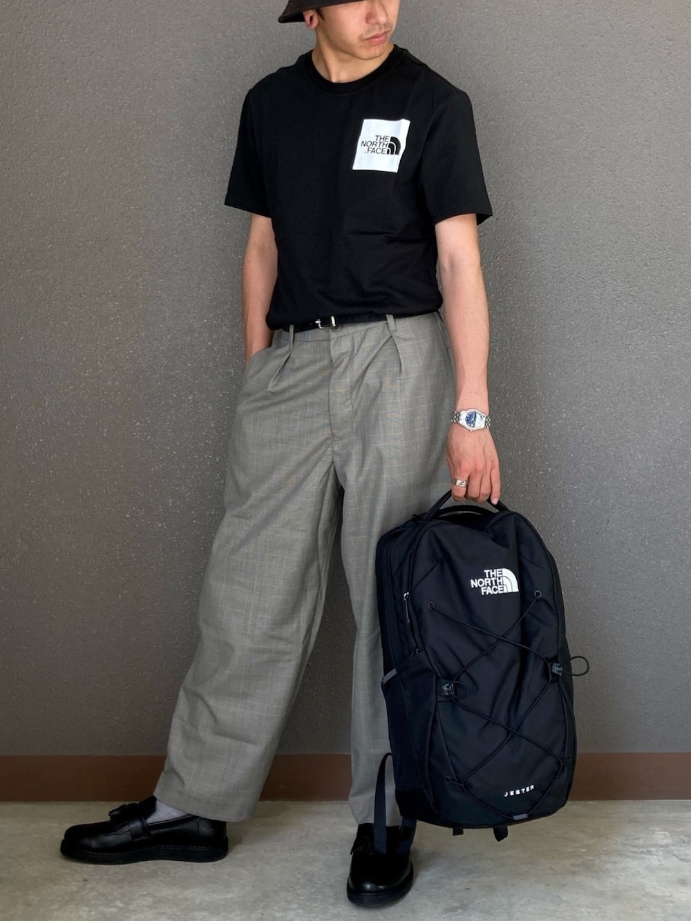 ブラック系のTシャツ/カットソー、ブラック系のスラックス、ブラック系のバックパック/リュックを着用したメンズの春コーディネートの1枚目の写真