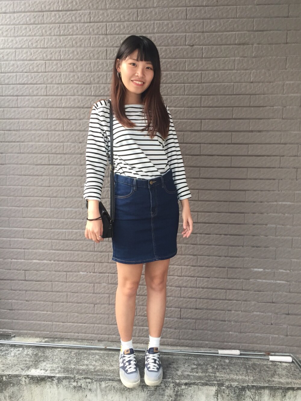 ブルー系のデニムスカート、ホワイト系のスニーカーを着用したレディースの春コーディネートの1枚目の写真