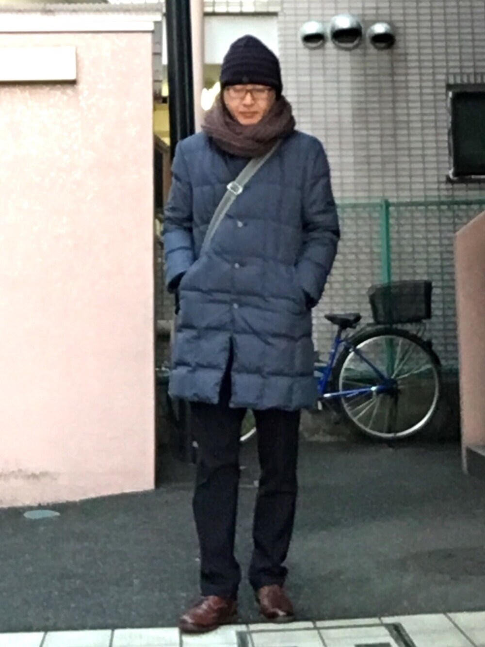 ブルー系のダウンジャケット/コート、ブラック系のスラックス、ブラウン系のドレスシューズを着用したメンズの冬コーディネートの1枚目の写真