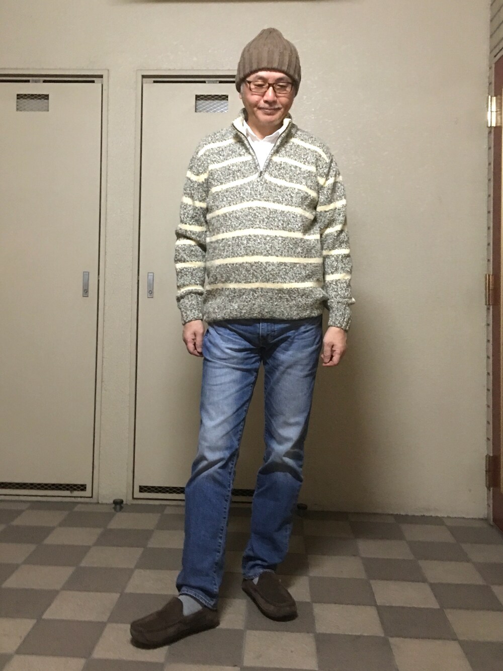 グレー系のニット/セーター、ブルー系のデニムパンツ、ブラウン系のモカシン/デッキシューズを着用したメンズの冬コーディネートの1枚目の写真